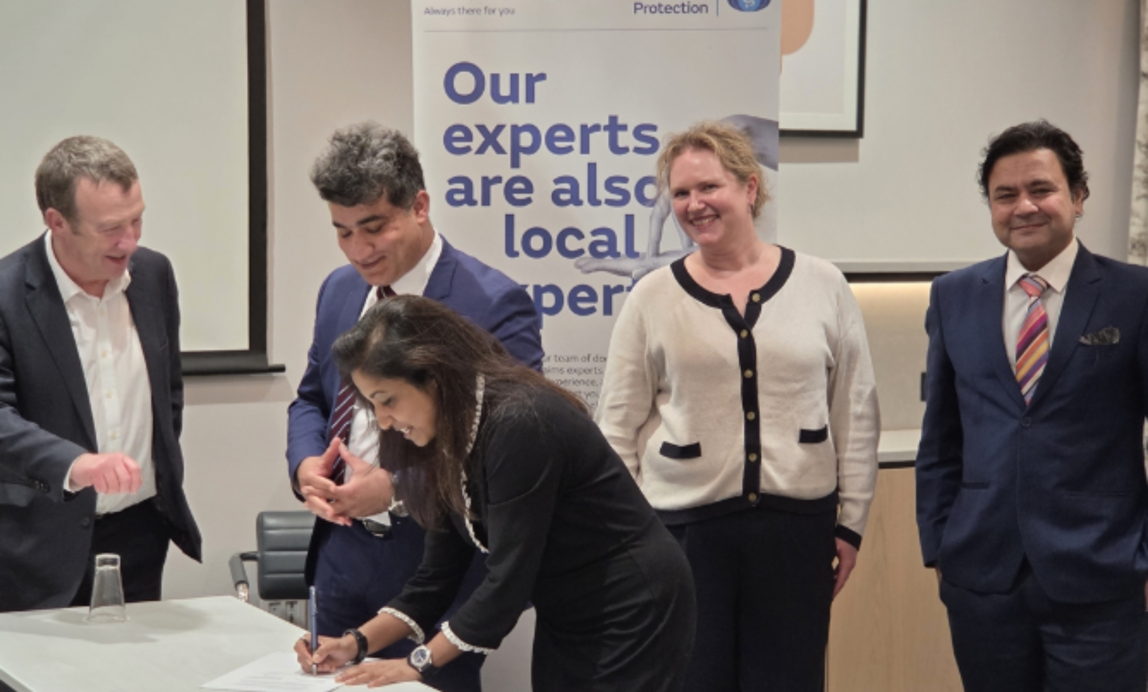 Representatives sign and smile to camera